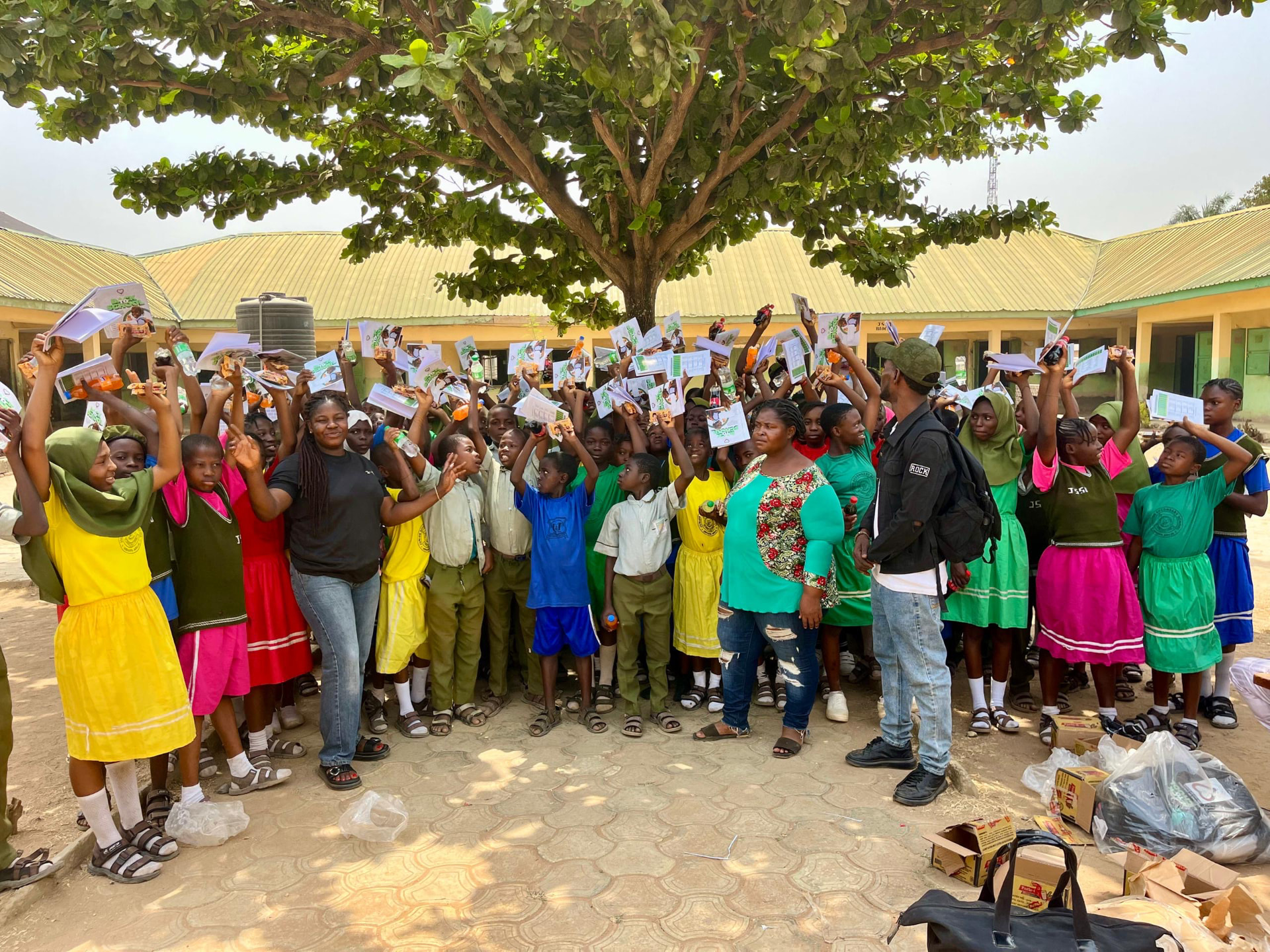 Schoolchildren raising new exercise books and learning materials during a Back to School distribution